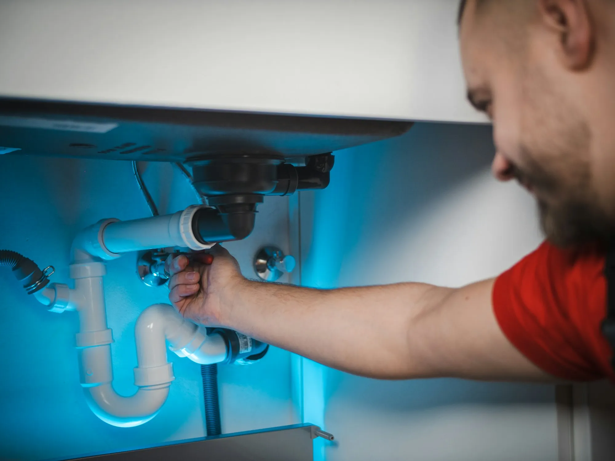 Technician fitting plumbing under a kitchen sink