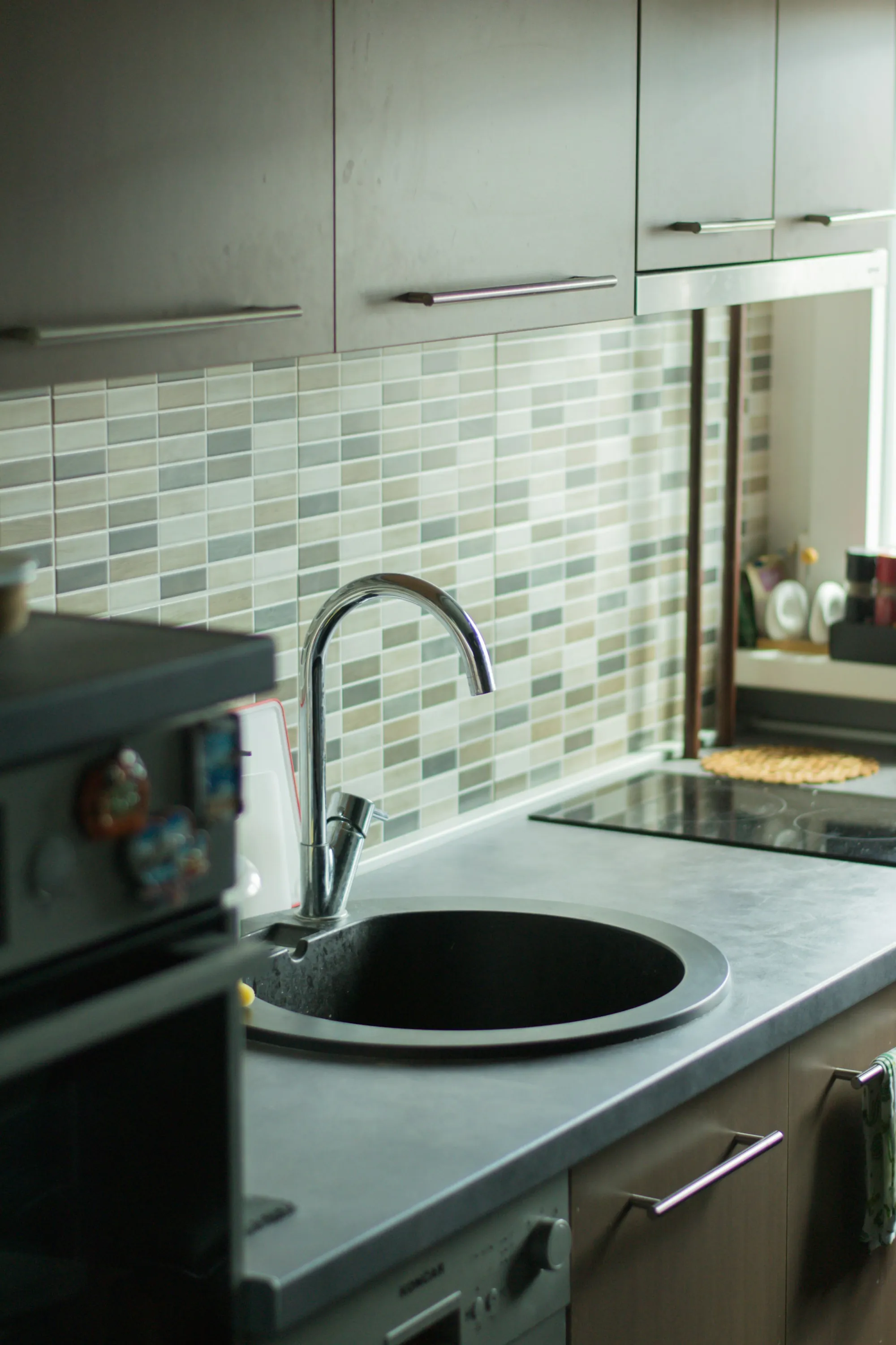 Chrome kitchen faucet against a green tile backsplash