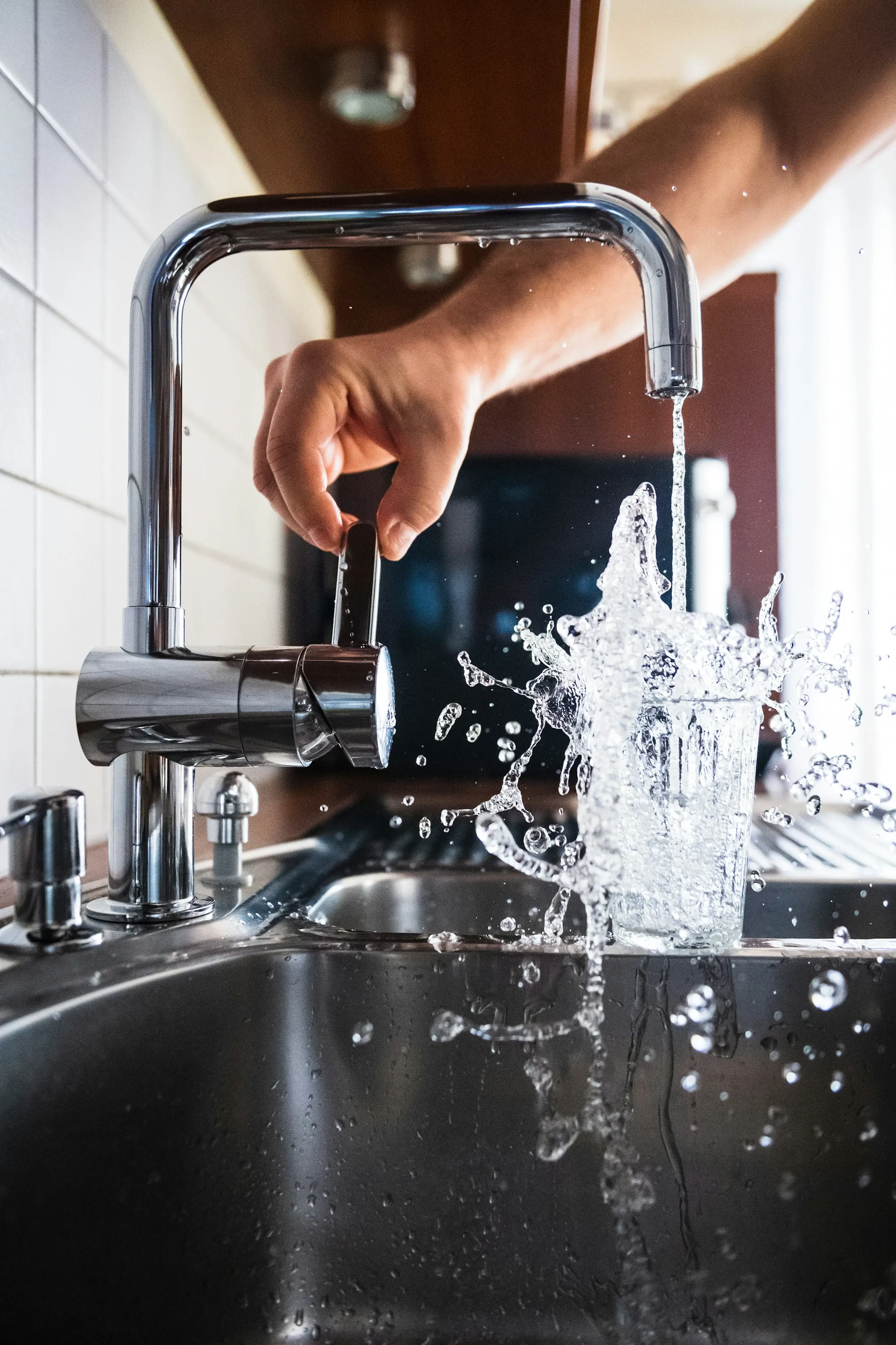 Glass filling with splashing water from a kitchen tap