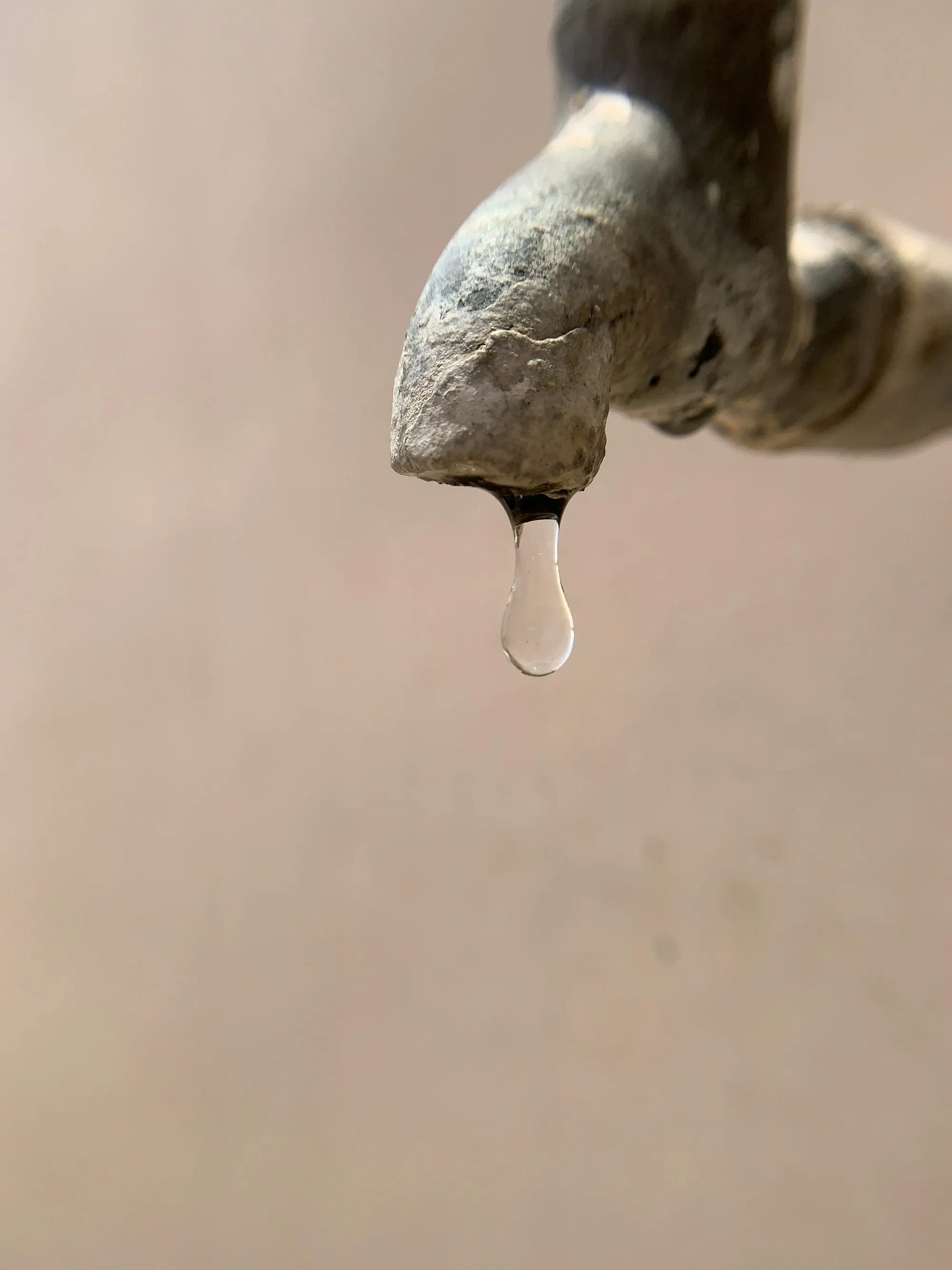 Rust-stained faucet with a drop of water