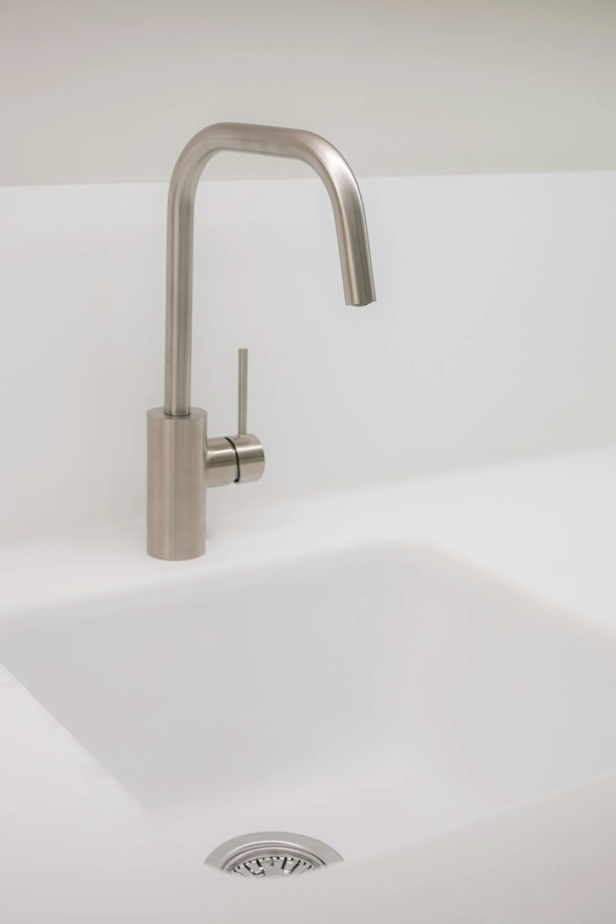 Brushed steel drinking water faucet over a white sink