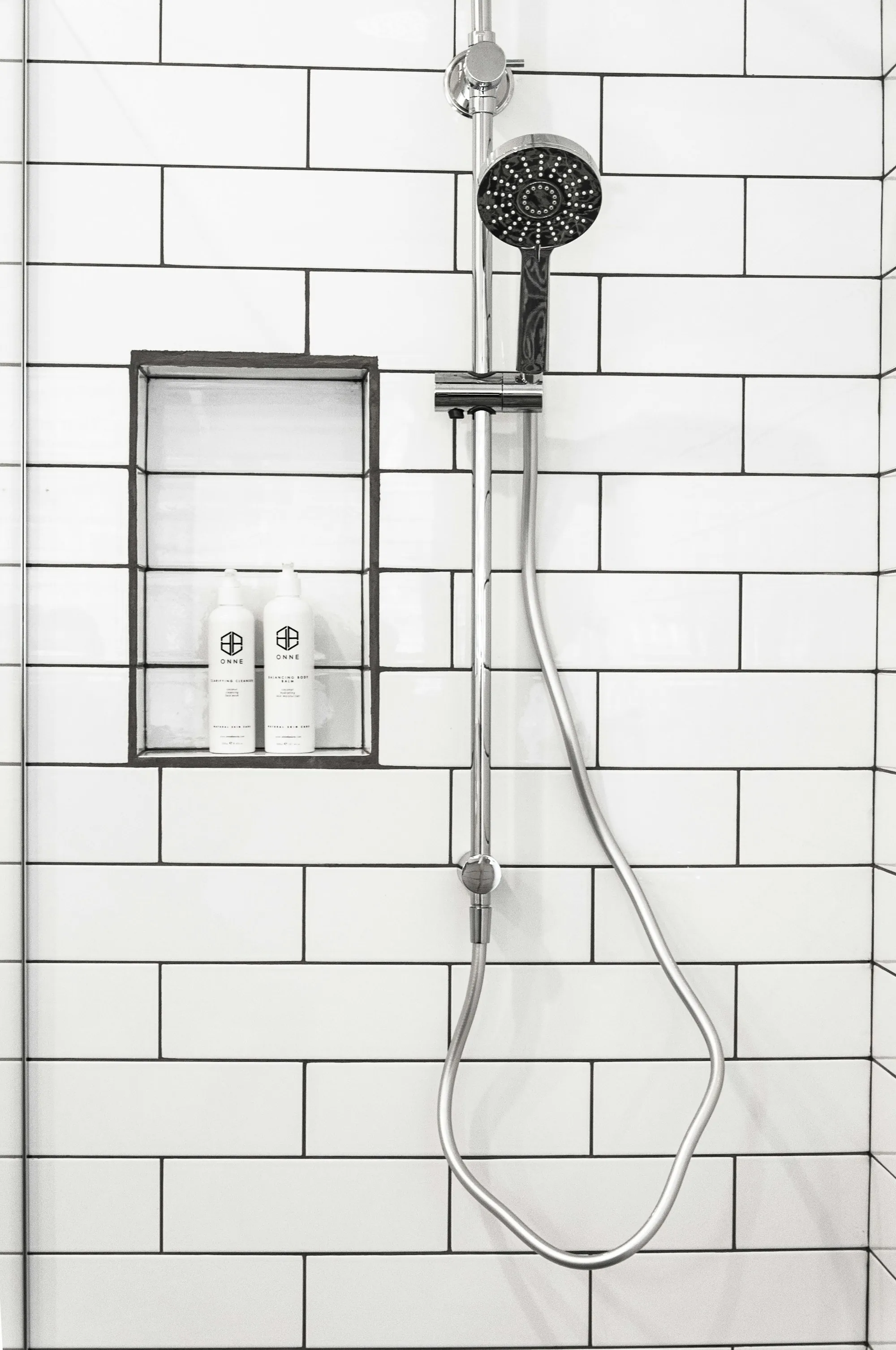 White tiled shower with a handheld shower head