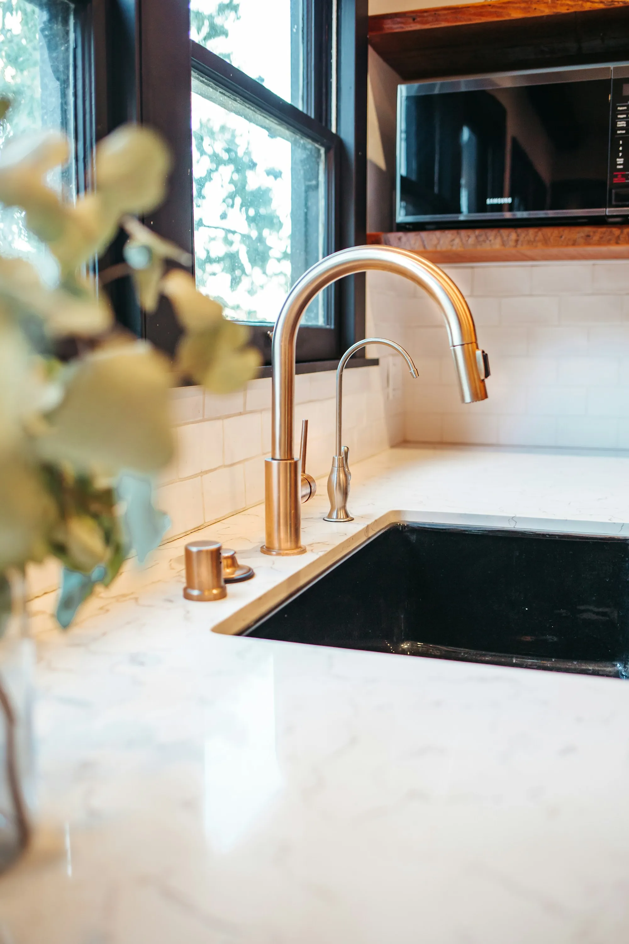 Brushed brass kitchen faucet over a dark sink