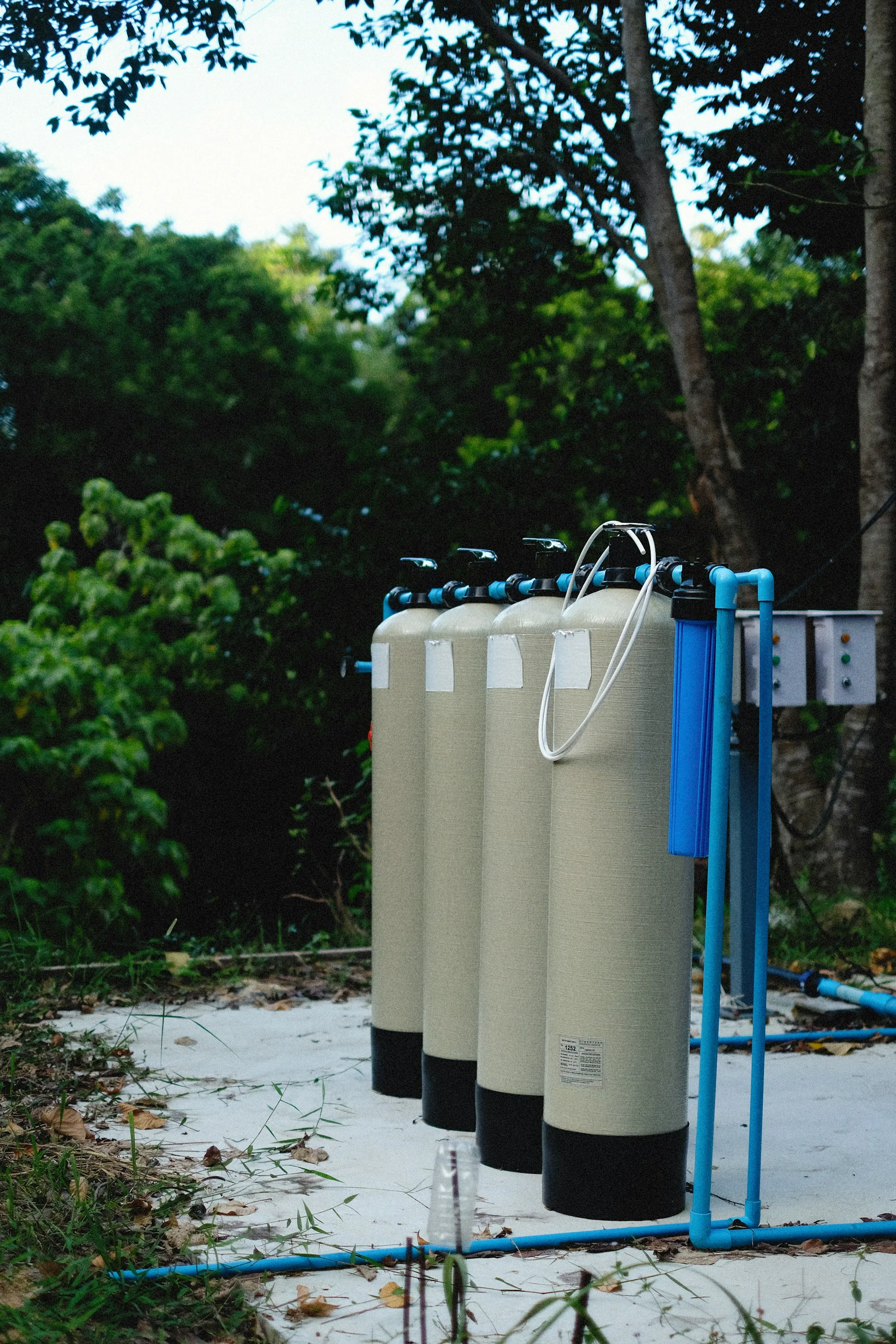 Whole-house filtration tanks installed outdoors with blue plumbing